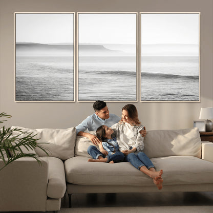 A black and white minimalist seascape featuring soft rolling waves and misty distant cliffs, creating a serene and timeless coastal atmosphere.