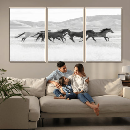A black and white image of wild horses running freely across an open grassland, capturing the power and beauty of untamed nature in a rustic western setting.