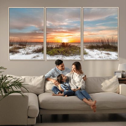 A tranquil beach scene featuring golden sunset hues over the water, with grasses in the foreground and a peaceful, serene atmosphere.