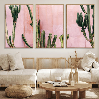 Framed canvas of tall green cacti against a soft pink wall, ideal for modern desert or colorful southwest-inspired home decor.