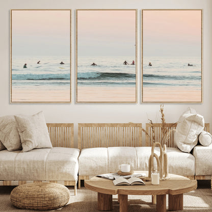 Dreamy photo of surfers waiting on soft pastel waves under a pink sunset sky, ideal for soft coastal minimalist or serene ocean-themed home decor.