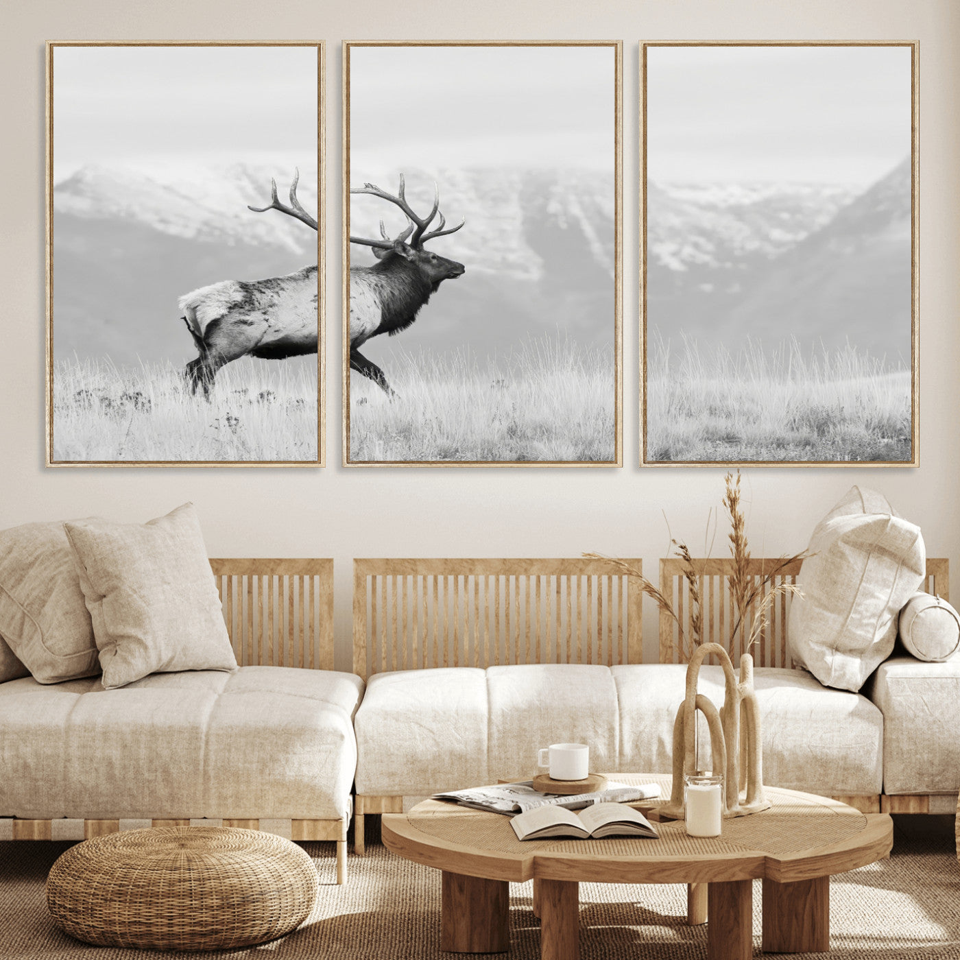 Black and white photograph of a majestic elk standing in a grassy field with snow-capped mountains in the background, creating a bold and rustic wilderness scene.