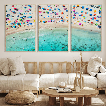 Aerial view of a vibrant beach filled with colorful umbrellas and people enjoying the turquoise ocean, capturing a lively summer vacation scene.