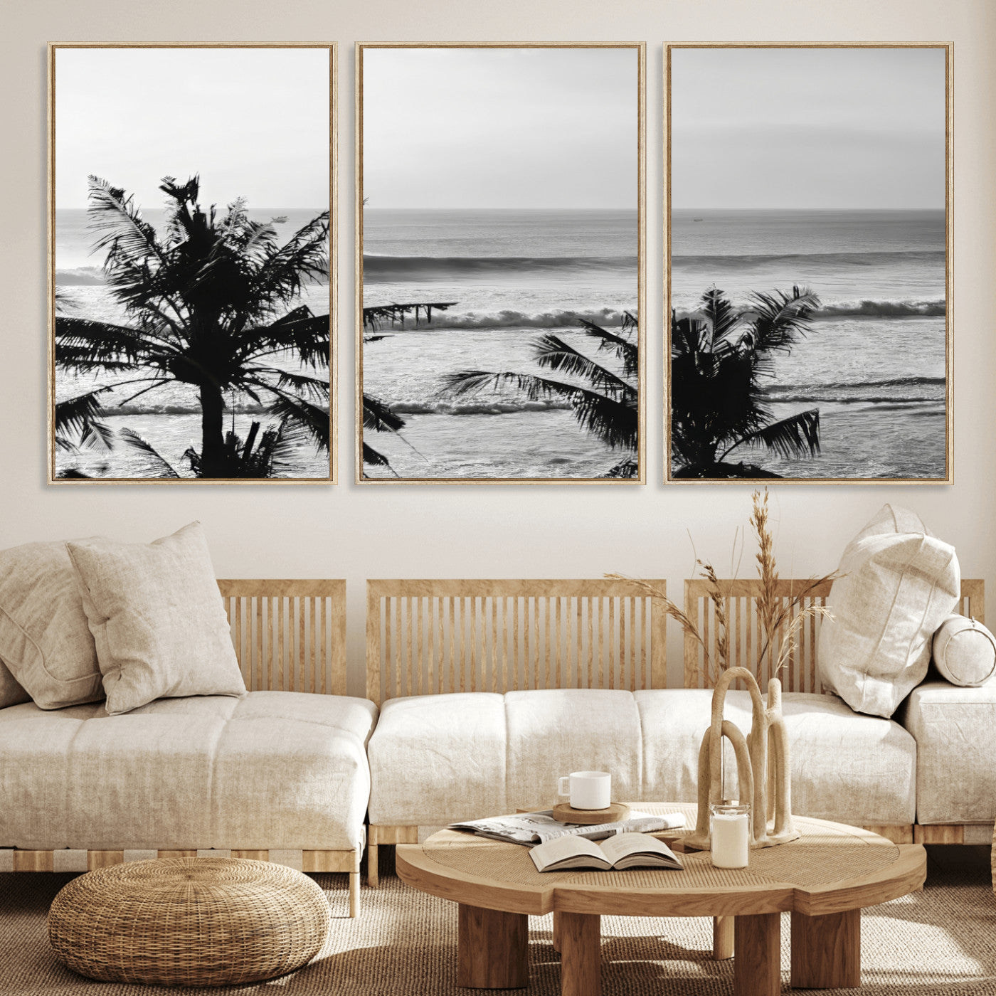 Black and white view of ocean waves crashing on a tropical coastline, framed by silhouetted palm trees under a vast, open sky.