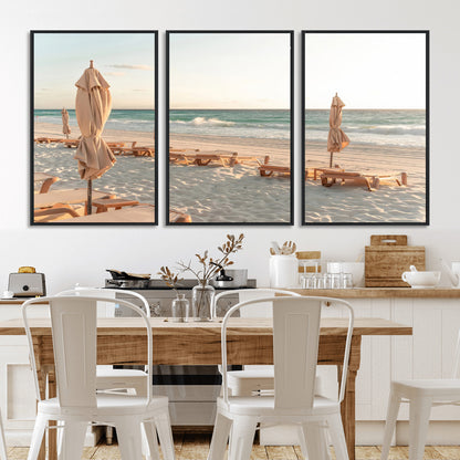 Minimalist photo of empty beach loungers and umbrellas on soft sand, ideal for calm seaside or pastel coastal-style home decor.
