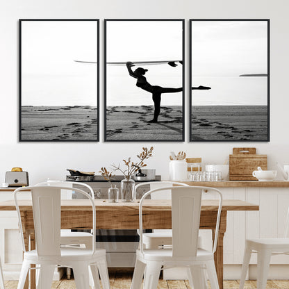 A woman balances a surfboard on her head while striking a yoga pose on the beach, silhouetted against a calm ocean horizon.