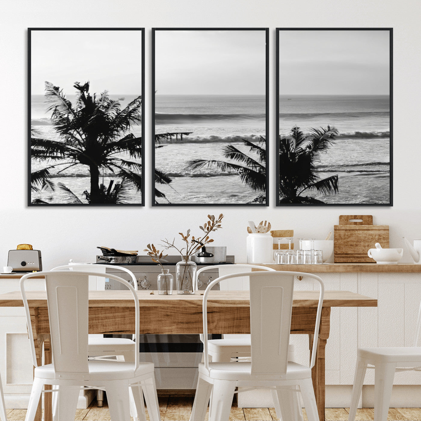 Black and white view of ocean waves crashing on a tropical coastline, framed by silhouetted palm trees under a vast, open sky.