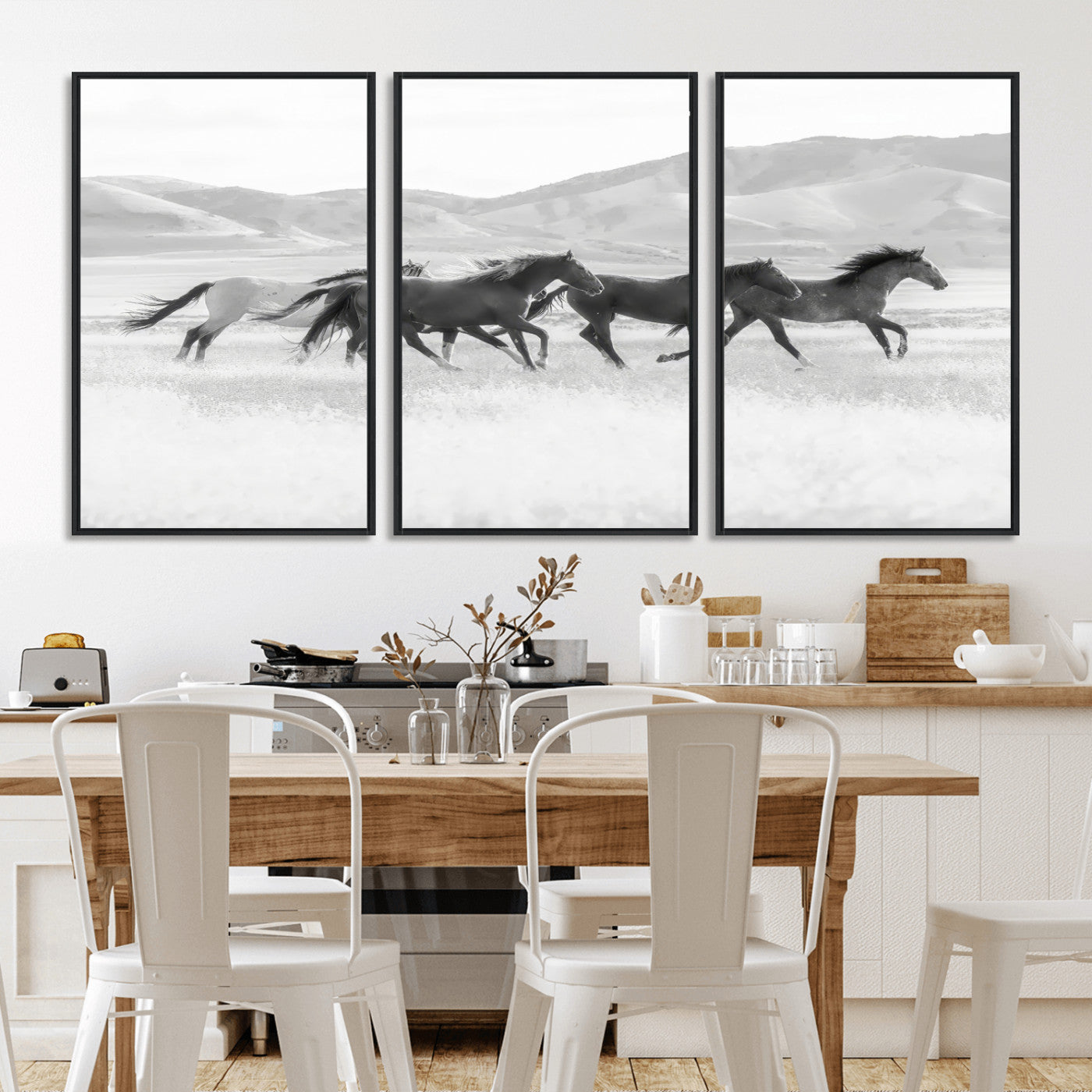 A black and white image of wild horses running freely across an open grassland, capturing the power and beauty of untamed nature in a rustic western setting.