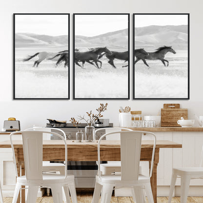 A black and white image of wild horses running freely across an open grassland, capturing the power and beauty of untamed nature in a rustic western setting.