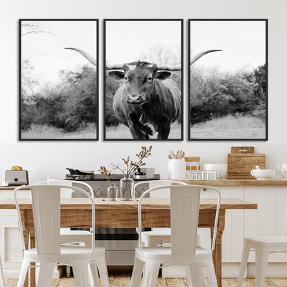 Black and white photo of a longhorn cow in a field, perfect for rustic farmhouse or western-themed interior wall decoration.