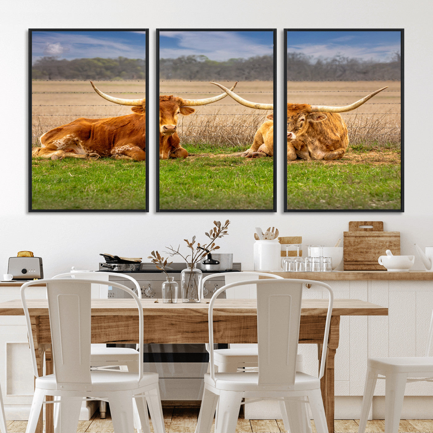 Two longhorn cows lying on green grass in front of a golden field and trees under a blue sky, perfect for rustic country wall decor.