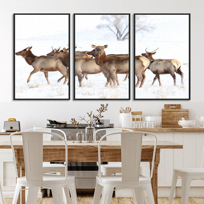 A group of elk standing on snowy terrain with a tree in the background, perfect for rustic or lodge-style winter wall decor.