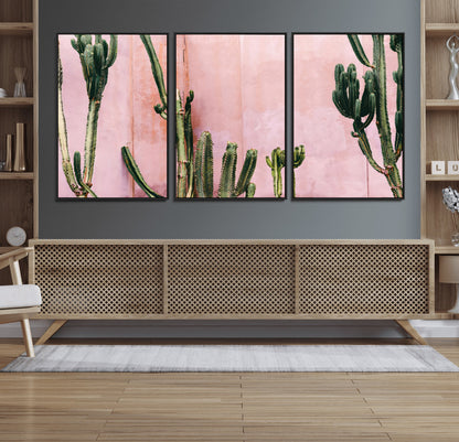Framed canvas of tall green cacti against a soft pink wall, ideal for modern desert or colorful southwest-inspired home decor.
