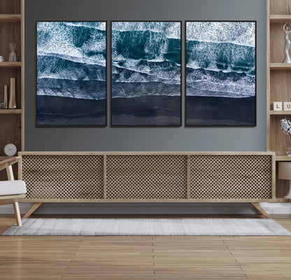 Canvas of aerial ocean waves crashing onto a black sand beach in moody tones, ideal for modern coastal or minimalist home decor.