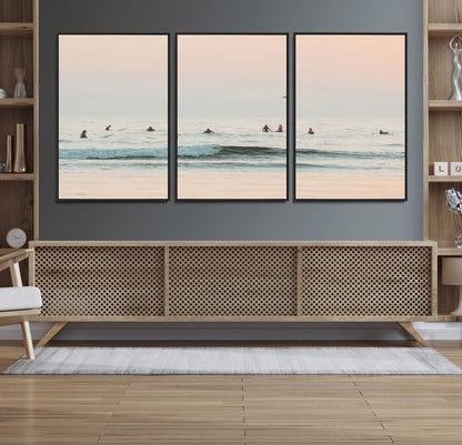 Dreamy photo of surfers waiting on soft pastel waves under a pink sunset sky, ideal for soft coastal minimalist or serene ocean-themed home decor.