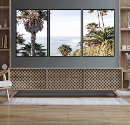 Scenic coastal view with tall palm trees overlooking a calm ocean, soft blue waves, and surfers in the distance, creating a peaceful tropical vibe.