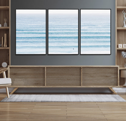Minimalist ocean view with soft blue waves and a lone surfer, creating a serene and airy coastal aesthetic, perfect for tranquil home decor.