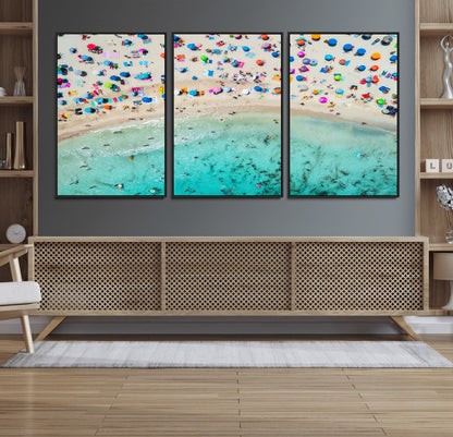 Aerial view of a vibrant beach filled with colorful umbrellas and people enjoying the turquoise ocean, capturing a lively summer vacation scene.