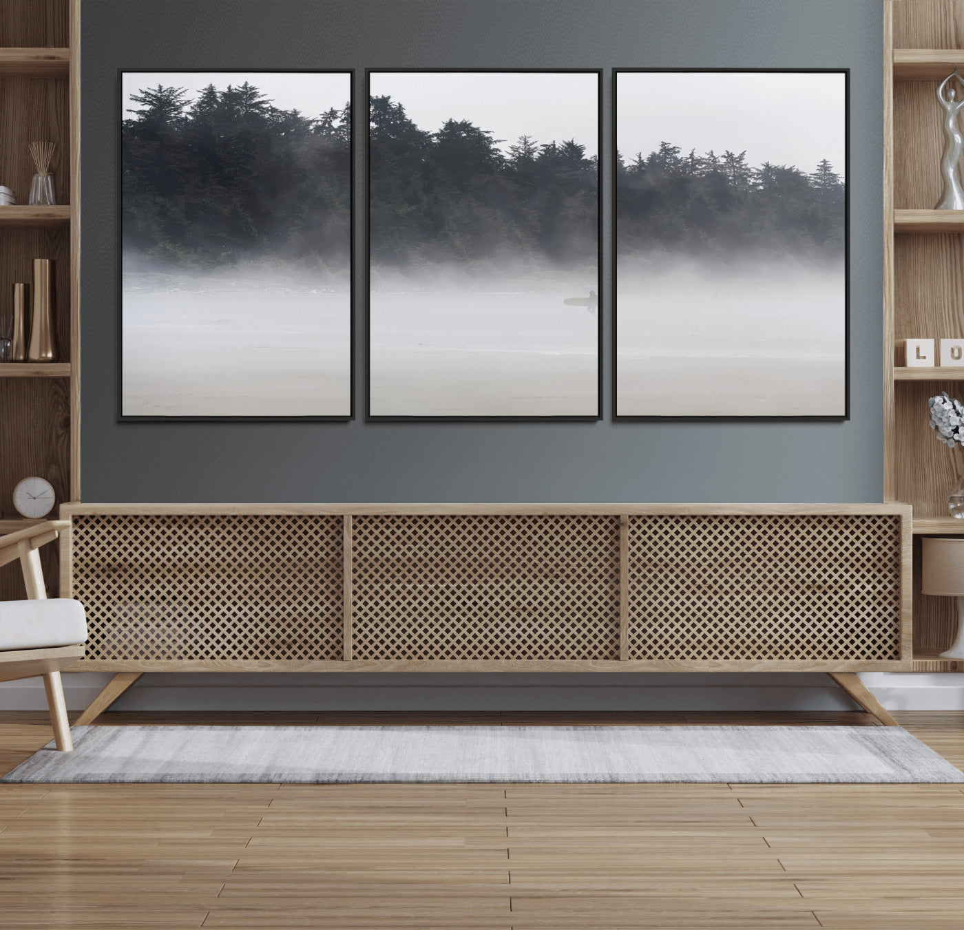 A lone surfer carrying a board through a misty shoreline, surrounded by dense trees and fog, creating a peaceful and mysterious coastal scene.