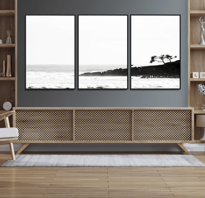 Black and white photo of a surfer standing on rocky cliffs, gazing at the waves, embodying the spirit of adventure and solitude.