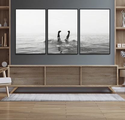 A black and white minimalist water scene capturing a playful splash as a swimmer dives upside down, creating a carefree and artistic aquatic aesthetic.