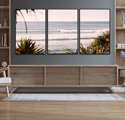 Canvas of a lone surfer riding a pastel wave at sunrise, perfect for tropical or coastal-themed spaces with a relaxed, airy vibe.