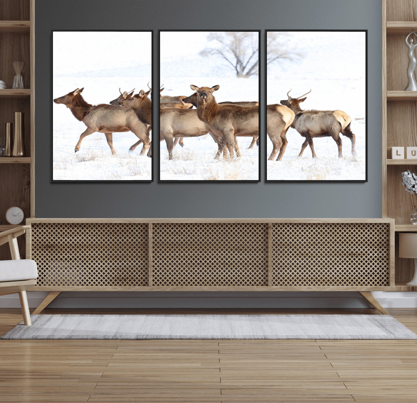 A group of elk standing on snowy terrain with a tree in the background, perfect for rustic or lodge-style winter wall decor.