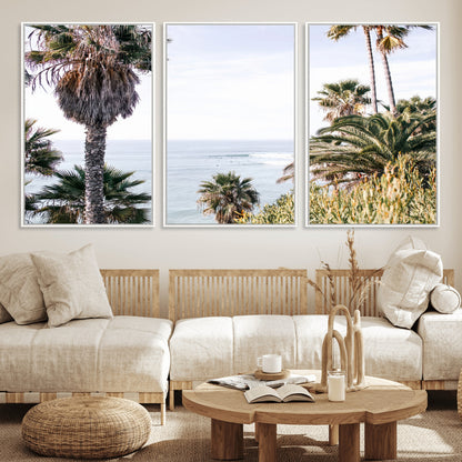 Scenic coastal view with tall palm trees overlooking a calm ocean, soft blue waves, and surfers in the distance, creating a peaceful tropical vibe.