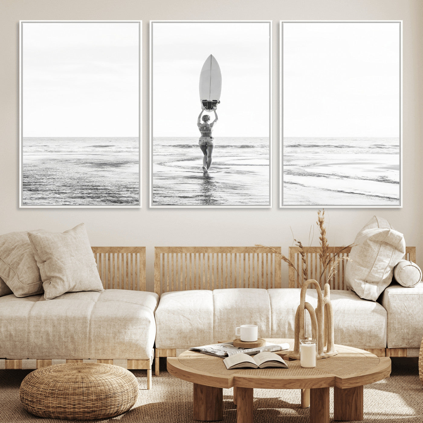 Black and white image of a female surfer holding a surfboard above her head while walking toward the ocean, creating a minimalist and bold coastal aesthetic.