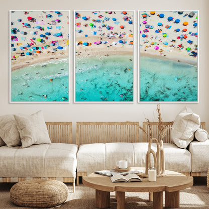 Aerial view of a vibrant beach filled with colorful umbrellas and people enjoying the turquoise ocean, capturing a lively summer vacation scene.