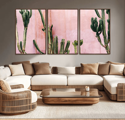 Framed canvas of tall green cacti against a soft pink wall, ideal for modern desert or colorful southwest-inspired home decor.