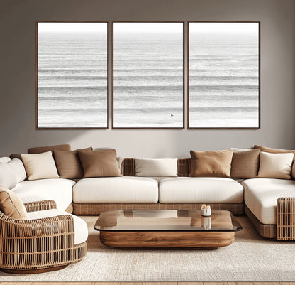Monochrome photo of a lone surfer in calm layered waves, perfect for minimalist coastal or moody ocean-inspired wall decoration.