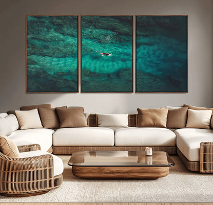 An aerial view of a solo surfer paddling through crystal-clear turquoise waters over a sunlit reef, capturing the beauty and serenity of open water surfing.