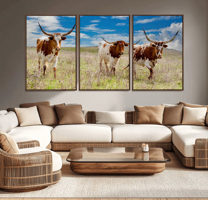 Three Texas longhorn cattle standing in dry grass under a bright blue sky, ideal for farmhouse or western rustic home decor.