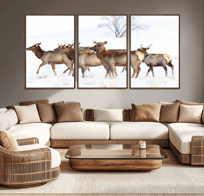 A group of elk standing on snowy terrain with a tree in the background, perfect for rustic or lodge-style winter wall decor.