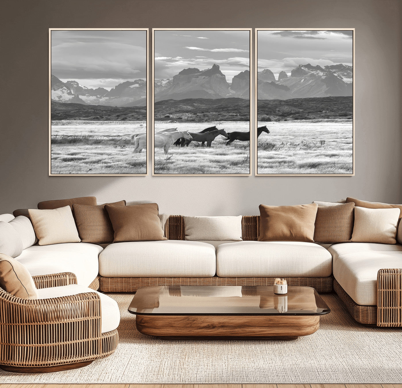 A black and white landscape of wild horses grazing in a vast grassland with towering mountains in the background, creating a moody and rustic western aesthetic.