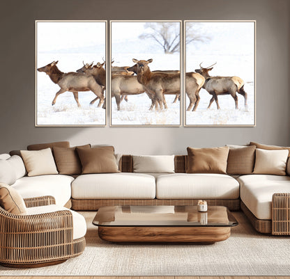 A group of elk standing on snowy terrain with a tree in the background, perfect for rustic or lodge-style winter wall decor.
