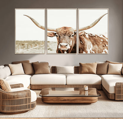 A Texas longhorn bull with wide horns, standing in a dry field under soft light, ideal for rustic farmhouse or western-themed interiors.