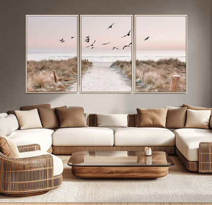 A peaceful coastal pathway leading to the ocean, with birds flying across a soft pastel sky, creating a calm and scenic beach atmosphere.