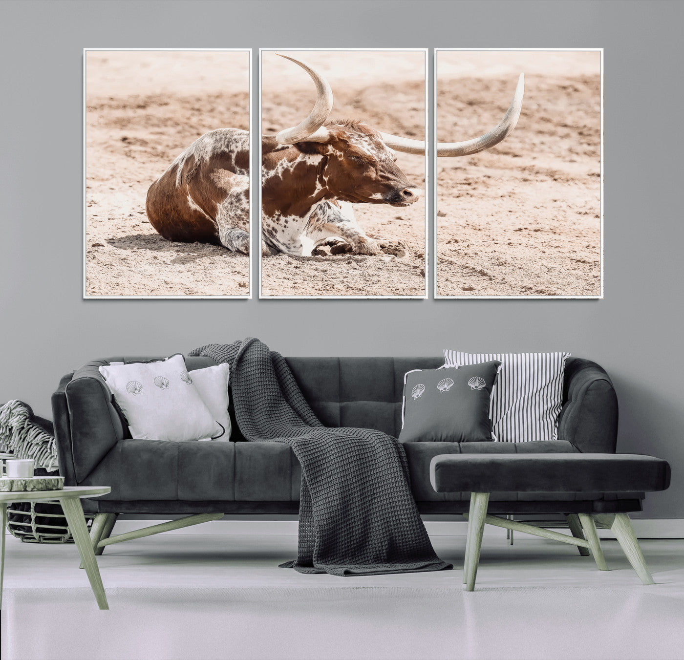 Texas Longhorn bull resting on dusty ground with warm tones, ideal for rustic western or farmhouse-themed wall decor.