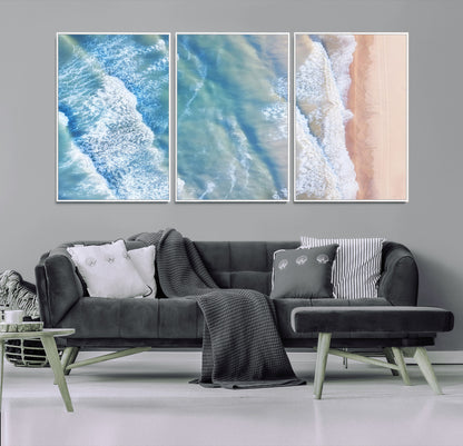 Aerial photo of soft blue waves meeting sandy shore, perfect for modern coastal or beach-themed decor with a light and tranquil aesthetic.