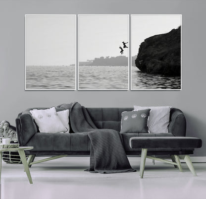 Black and white canvas of two figures cliff jumping into the sea, captured with moody tones, ideal for modern coastal or adventure-themed home decor.   2/2