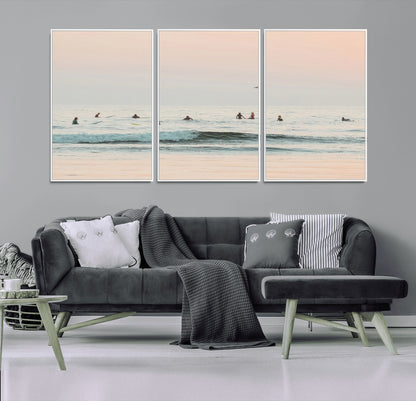 Dreamy photo of surfers waiting on soft pastel waves under a pink sunset sky, ideal for soft coastal minimalist or serene ocean-themed home decor.