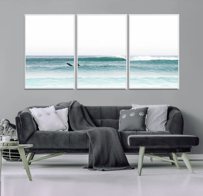 Minimalist photo of a lone surfer on calm aqua waves under bright sky, perfect for Scandinavian coastal or serene ocean-inspired home decor.