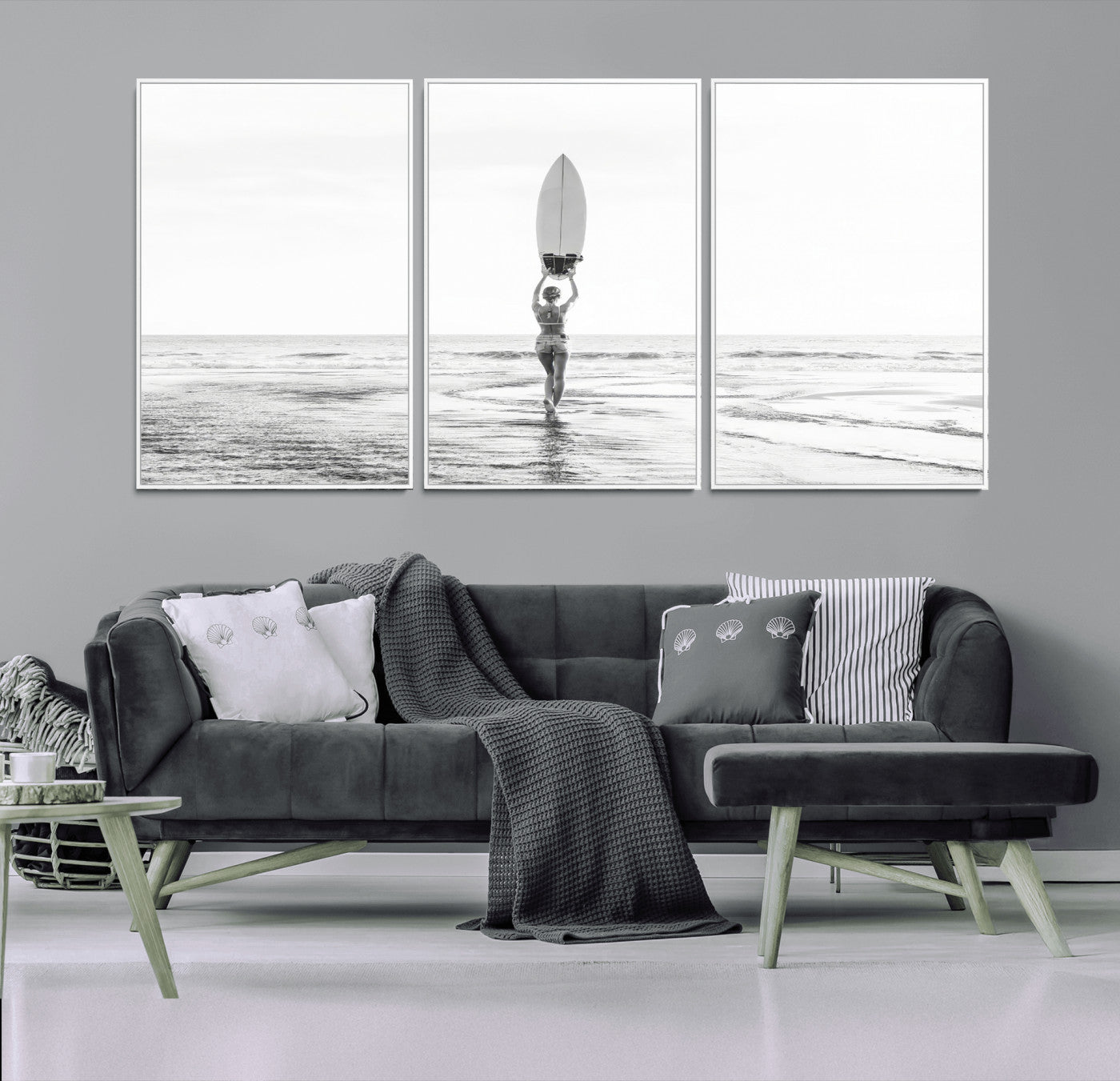 Black and white image of a female surfer holding a surfboard above her head while walking toward the ocean, creating a minimalist and bold coastal aesthetic.