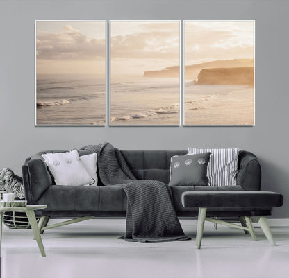 Golden hour seascape with misty cliffs and gentle waves rolling towards the shore, capturing a tranquil and warm coastal atmosphere.