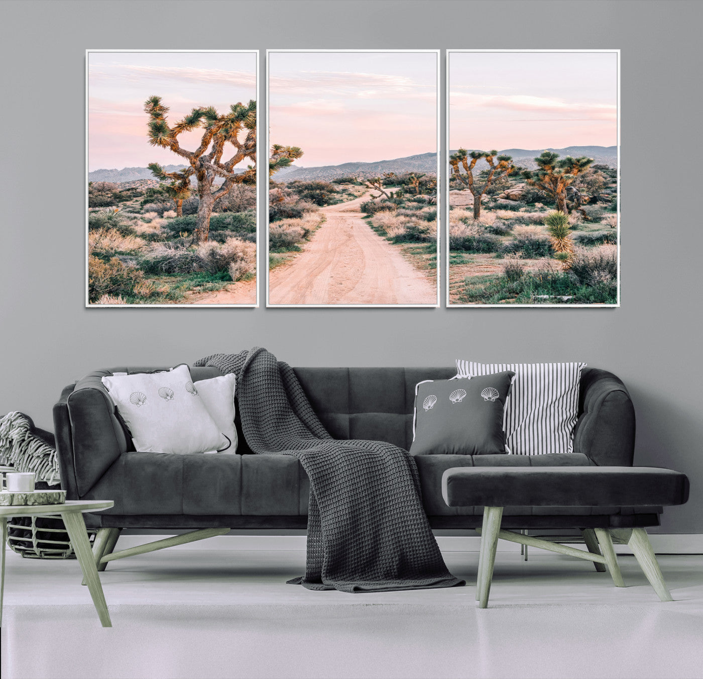 A dusty road winding through Joshua Tree National Park, framed by iconic twisted trees and warm desert tones under a soft pastel sky.