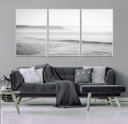 A black and white minimalist seascape featuring soft rolling waves and misty distant cliffs, creating a serene and timeless coastal atmosphere.