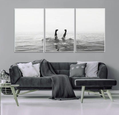 A black and white minimalist water scene capturing a playful splash as a swimmer dives upside down, creating a carefree and artistic aquatic aesthetic.