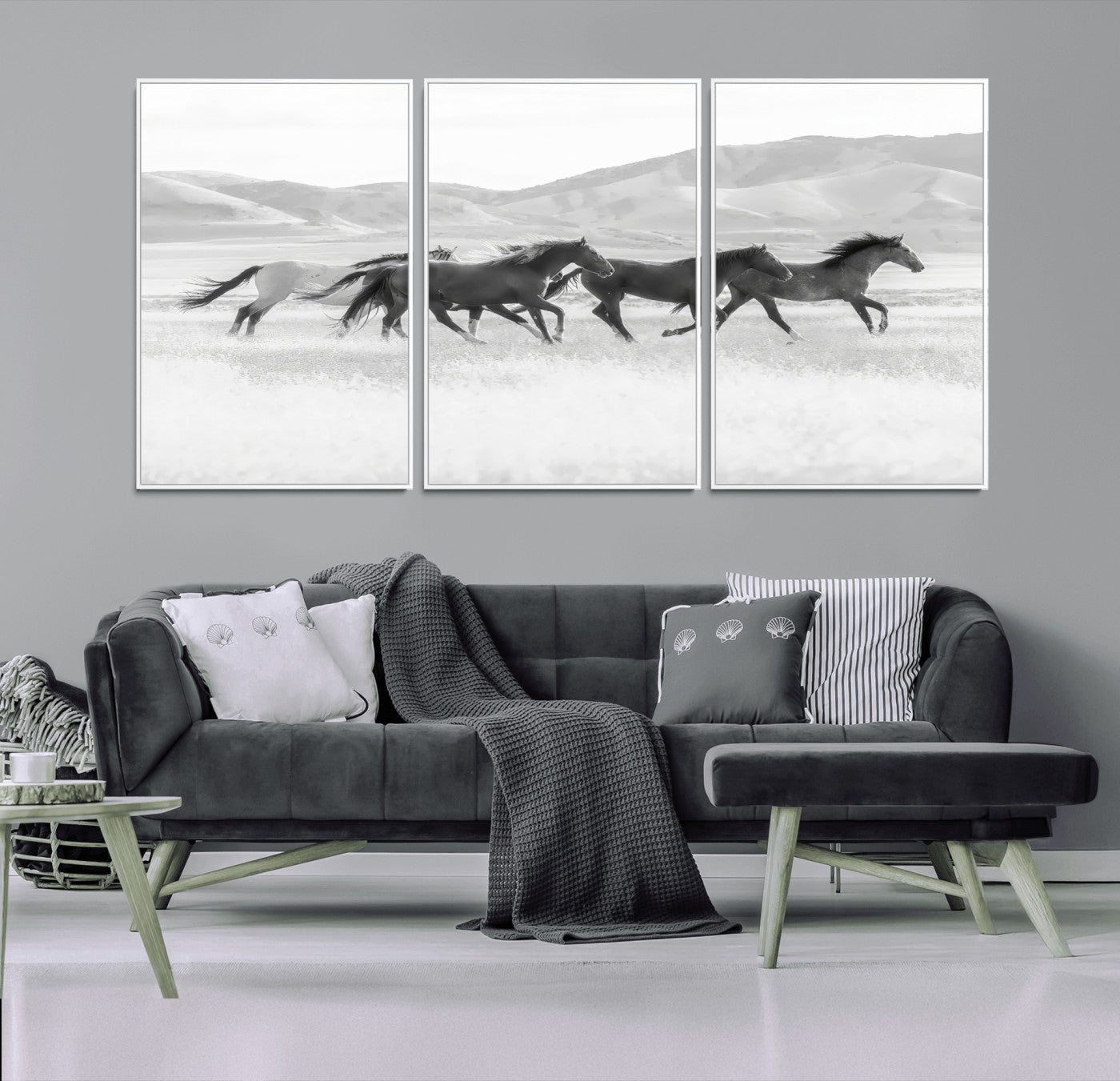 A black and white image of wild horses running freely across an open grassland, capturing the power and beauty of untamed nature in a rustic western setting.